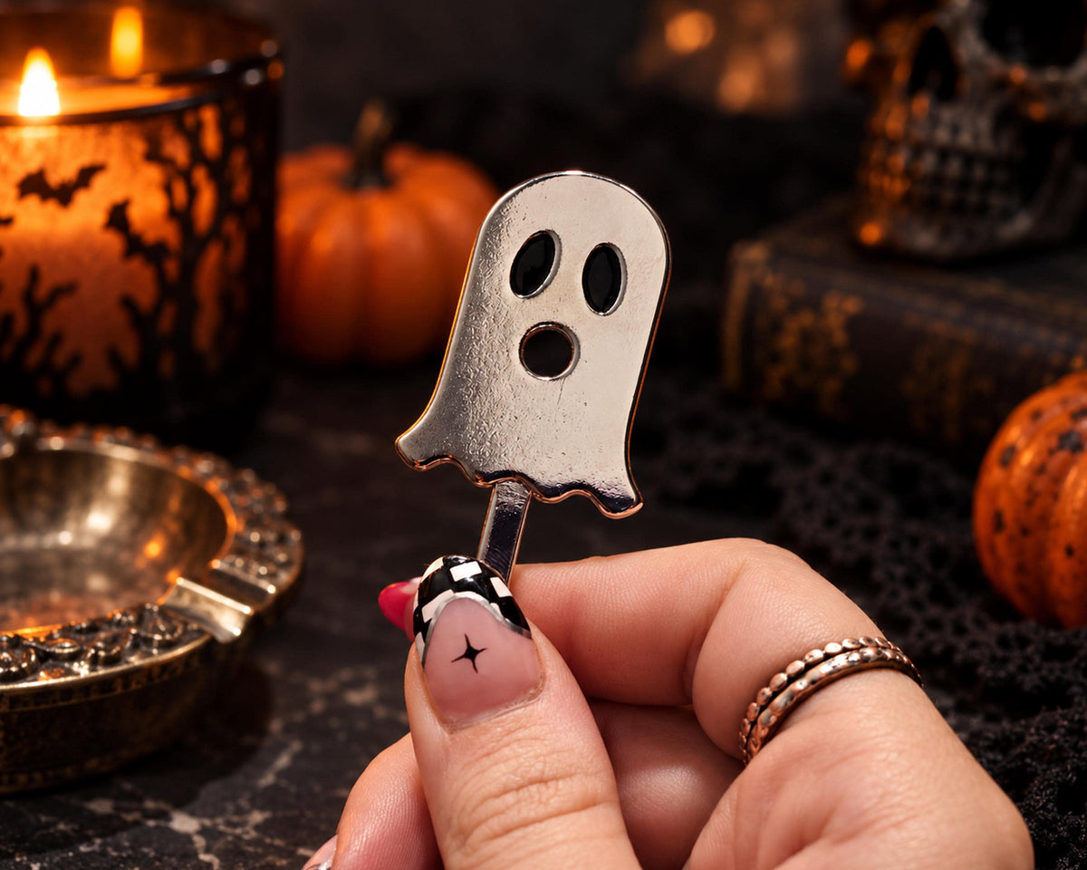 Silver-tone ghost cigarette holder held on a dark seasonal display
