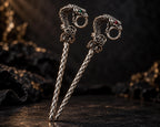 Pair of silver-tone snake cigarette holders on a dark display