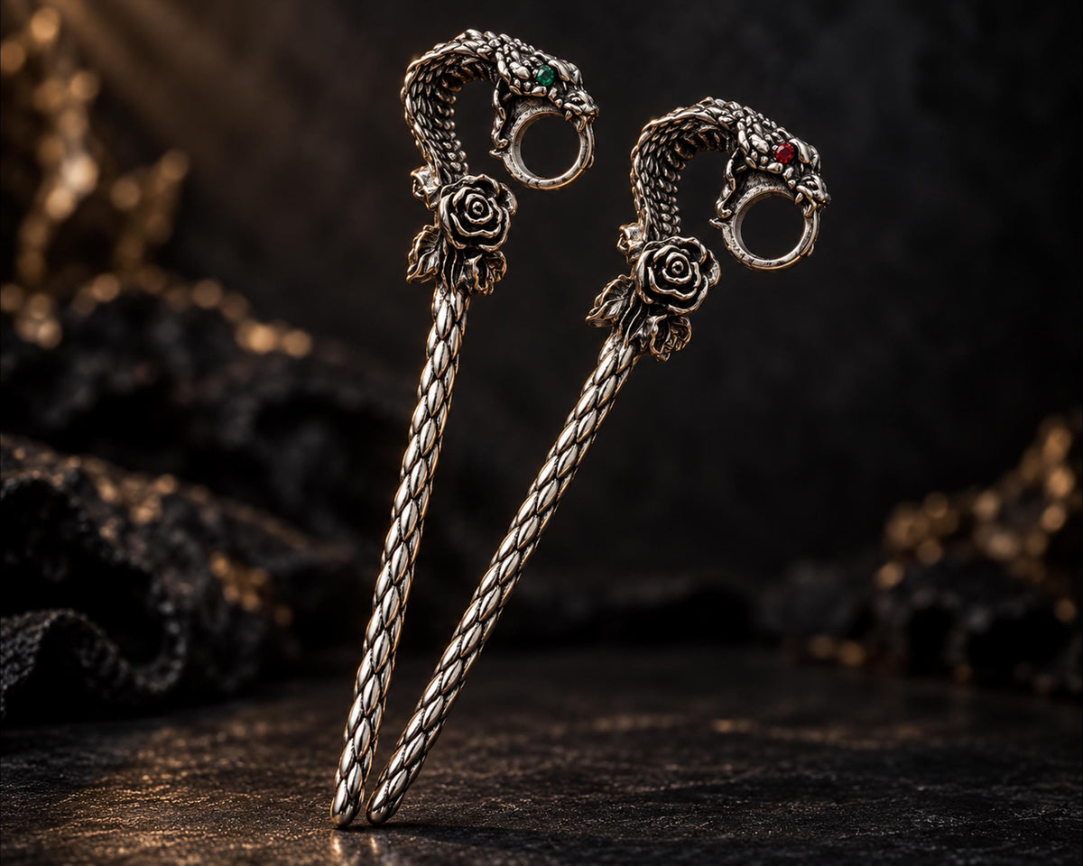 Pair of silver-tone snake cigarette holders on a dark display